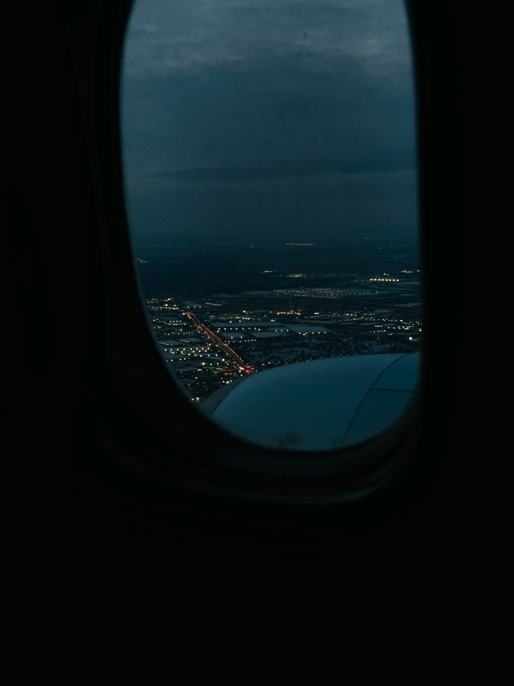 Blick aus einem Flugzeugfester: Die Stadt leuchtet in der Dämmerung.
